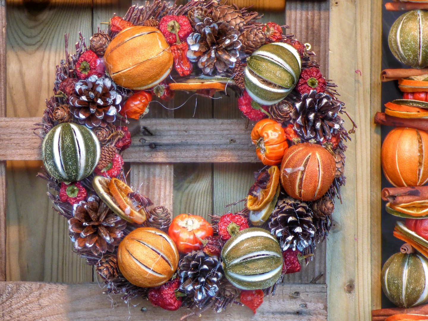 Handcrafted holiday wreath with pinecones and dried fruit on wood.